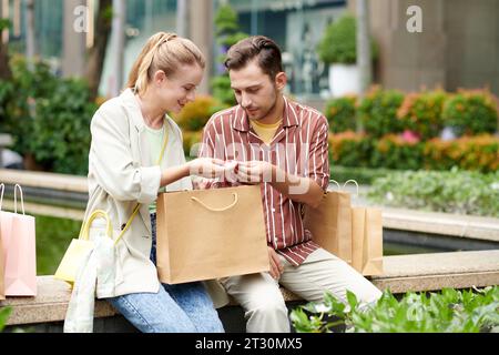 Eine lächelnde junge Frau zeigt ein Baumwollhemd, das sie für einen Freund in einer Modeboutique gekauft hat Stockfoto