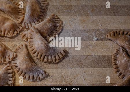 Traditionelle italienische Ravioli. Hausgemachte italienische Pasta. Frische Ravioli auf Holzbrett, Blick von oben Stockfoto
