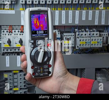 Elektriker, der mit einem Multimeter in einem Schaltschrank misst Stockfoto