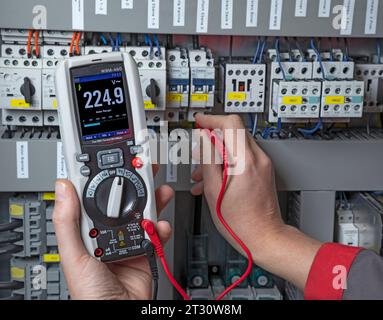 Elektriker, der mit einem Multimeter in einem Schaltschrank misst Stockfoto