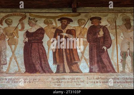 Detail aus dem 16. Jahrhundert Danza Macabra (Tanz des Todes) Freskenfries, in dem lächelnde Skelette stehen mit (von links): Königin, Herzog, Mann mit Glas (Arzt, Apotheker oder Apotheker) und Soldat in Rüstung, jeder Sterbliche durchbohrt von Pfeil des Todes. Gemalt von der italienischen Künstlerin Simone II. Baschenis (ca. 1495–1555) an der Außenwand der Chiesa di San Vigil in Pinzolo, Trentino-Südtirol, Italien. Der Fries hat Unterschriften in lokalen Dialekten und die von den gewöhnlichen Menschen verstandene Sprache. Stockfoto