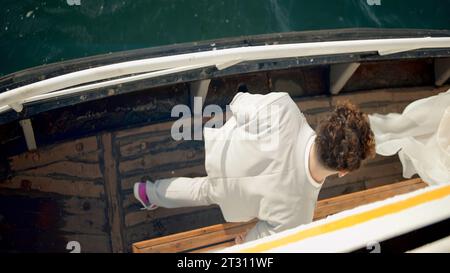 Von oben nach unten auf einem hölzernen Boot auf Braut und Bräutigam in weißer Kleidung. Aktion. Hochzeitsreise und Flitterwochen. Stockfoto