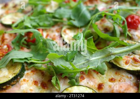 Leckere Pizza mit Tomaten, Rucolablättern, Zucchini und Lachs Stockfoto