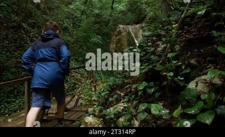 Reisender Junge, der im Wald auf einer Holzbrücke läuft. Kreativ. Junge Reisender, der durch den Wald läuft. Stockfoto