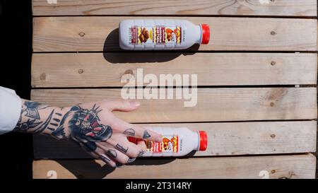 Tschechische Republik - Prag, 5. Juni 2023: Von oben nach unten: Eine von Tattoos bedeckte Männerhand, die eine Plastikschlacht beim Milchshake annimmt. Clip. Erdbeere wählen Stockfoto