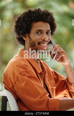 Porträt eines lächelnden Schwarzen Mannes, der am Telefon spricht und in die Kamera schaut Stockfoto