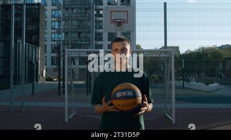 Ein schöner Mann. Medien. Ein Mann, der mit einem Ball auf einem speziellen Platz spielt, auf dem das Sonnenlicht fällt. Stockfoto