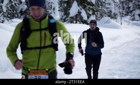 Wintersport. Clip. Männer in Sportuniformen mit Zahlen, die bei Wettkämpfen durch den Schnee laufen. Stockfoto