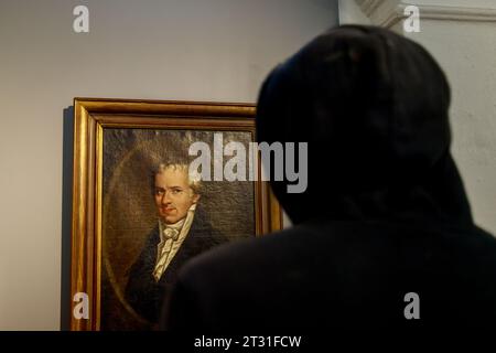 Bogota, Kolumbien - 8. Januar 2023: Junger Mann in einer Kapuze betrachtet ein gemaltes Porträt des Baron de Humboldt, das im Nationalmuseum ausgestellt ist Stockfoto