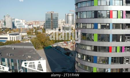 Modernes Hochhaus auf dem Hintergrund des Stadionbaus. Archivmaterial. Blick auf die moderne Stadt mit Hochhäusern und Stadionbaustelle Stockfoto