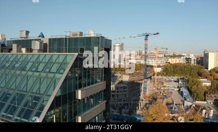 Modernes Hochhaus auf dem Hintergrund des Stadionbaus. Archivmaterial. Blick auf die moderne Stadt mit Hochhäusern und Stadionbaustelle Stockfoto