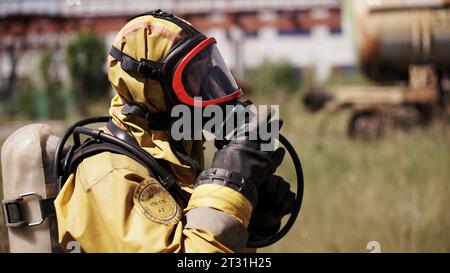 Ein Feuerwehrmann in Uniform. Clip. Ein erwachsener Mann mit Helm und Maske, der auf der Straße steht und sich auf die Arbeit vorbereitet. Stockfoto