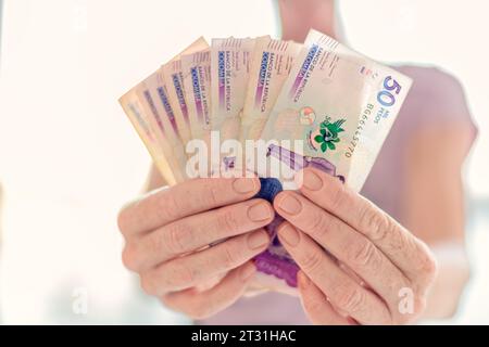 Nahaufnahme von Frauenhänden mit Scheinen von 50 000 kolumbianischen Pesos und 100 Dollar Stockfoto