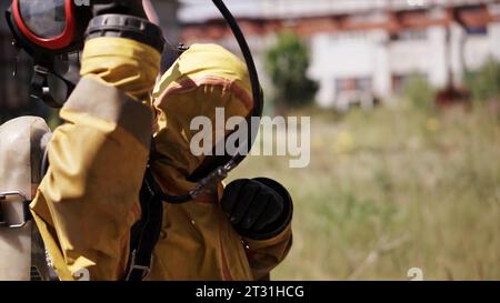 Ein Feuerwehrmann in Uniform. Clip. Ein erwachsener Mann mit Helm und Maske, der auf der Straße steht und sich auf die Arbeit vorbereitet. Stockfoto