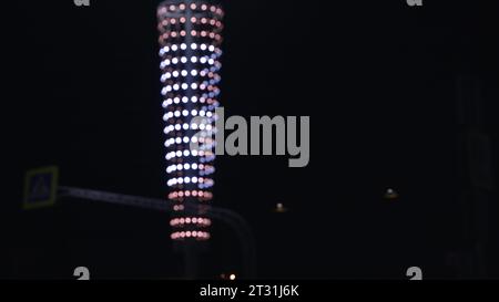 Bei Nacht sind die Lichterketten am Laternenpfahl verschwommene Lichter. Archivmaterial. Glänzende Girlande um die Laternenpfahl. Unschärfe der Girlande am Pol in der Nachtstadt Stockfoto