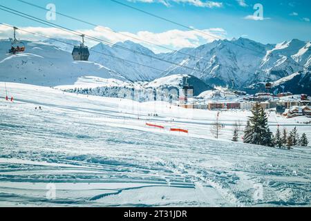 Fantastischer Skikurs mit Skipisten auf den frischen, tief verschneiten Hügeln. Winterskigebiet mit Skifahrern und Seilbahnen, Alpe d Huez, Frankreich, Europa Stockfoto