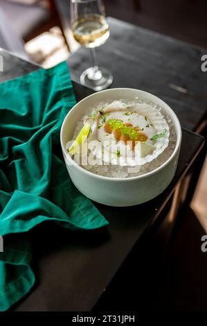 Jakobsmuschel in Soße mit fliegenden Fischkaviar auf einer Schale auf Eis in einem Restaurant. Hochwertige Fotos Stockfoto