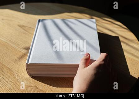 Buch-Mockup, Handöffner Hardcover auf Holztisch Stockfoto