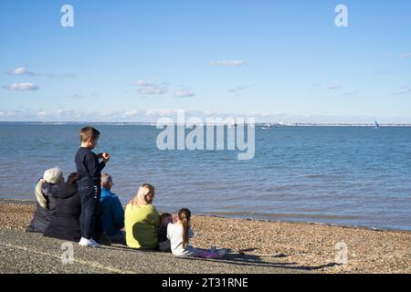 Kent UK. Oktober 2023. Wetter in Großbritannien. Eine Gruppe von Zuschauern saß am Strand und beobachtete das Dinghy Sailing Rennen auf der Isle of Sheppey, genoss eine warme herbstliche Sonne am Sonntag mit blauem Himmel, während sonst, wo im Land schwere Regenfälle und Überschwemmungen durch den Sturm Babet erlitten hatten. Quelle: Glosszoom / Alamy Live News. Stockfoto