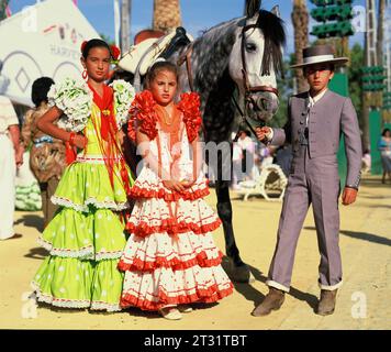 Spanien. Region Cadiz. Die Jerez Horse Fair. Zwei Mädchen und Junge in traditioneller Kleidung mit Pferd. Stockfoto