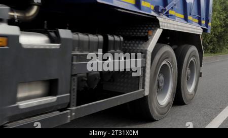 Lastenanhänger fährt auf der Straße. Szene. Lkw, der Güter auf dem Hintergrund grüner Büsche transportiert. Stockfoto