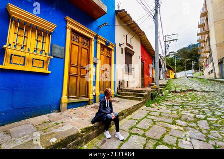 Touristen-Frau, die auf einer Straße in La Candelaria, Bogota, Kolumbien sitzt Stockfoto