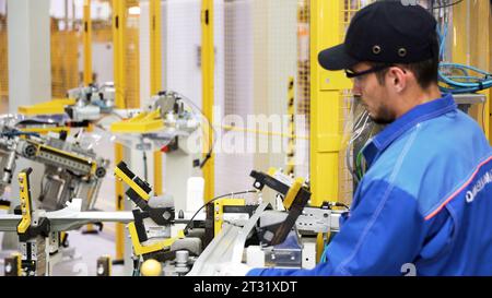 Berlin - Deutschland, 6. dezember 2022: Arbeiter in einer modernen Fabrik. Szene. Automatisierte Produktionslinie mit Roboterarmen, industrieller Hintergrund. Stockfoto