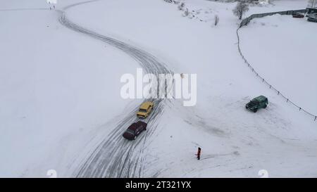 Blick von oben auf die winterlichen Autorennen. Clip. Rennwagen auf der Rennstrecke im Winterfeld. Autorennen auf der Straße im Winter Stockfoto