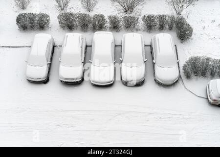 Winterparkplatz Autos unter schneebedeckten Autos Wintersaison. Geparkte Autos, schneebedeckter Blick von oben. Decken Sie den Wintergarten über der Sicht ab. Innenhof. Kaltes Wetter Stockfoto