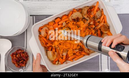 Rezept für geröstete Butternusskürbis-Suppe, Zubereitungsprozess. Geröstetes Gemüse in einer Keramikform, Nahaufnahme Stockfoto