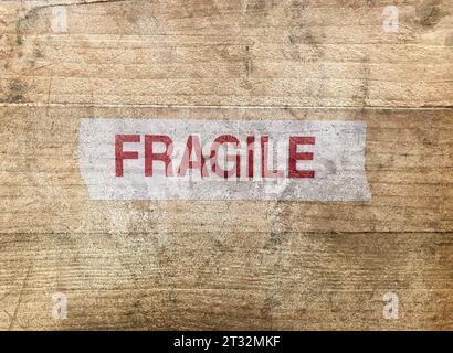 Nahaufnahme eines schmutzigen Holzkisten mit der Aufschrift „zerbrechlich“ als Symbol für beschädigte Sendung oder Treansport-Konzept. Stockfoto