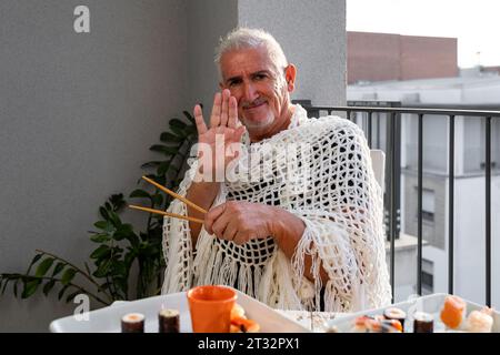 Attraktive Männer mittleren Alters haben Spaß beim Essen sitzen an einem Tisch gelegt Chinesisches Essen zum Mitnehmen auf einer Terrasse im Freien Stockfoto