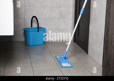 Wischmopp und Eimer auf gefliestem Boden in der Toilette Stockfoto