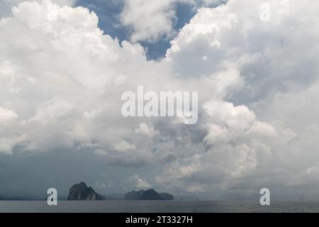 Regensturm zieht über malerische Kalksteinkarstformationen, die aus dem tropischen Meer ragen Stockfoto