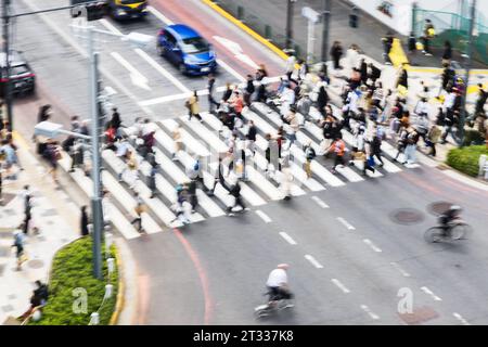 Bild mit absichtlicher Bewegungsunschärfe von Menschenmassen, die eine Stadtstraße in Tokio, Japan, überqueren Stockfoto