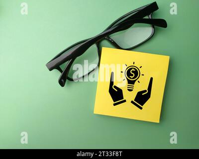 Draufsicht-Brille und Haftnotiz mit Geschäftssymbol auf grünem Hintergrund. Geschäftskonzept. Stockfoto