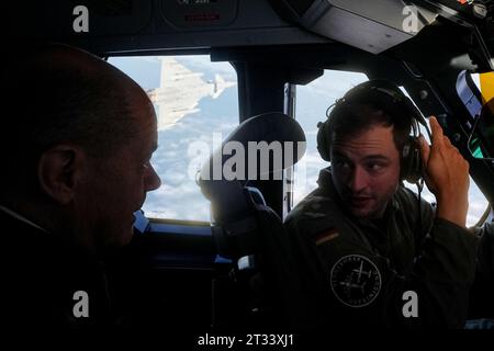 23. Oktober 2023, Brandenburg, Schönefeld: Bundeskanzler Olaf Scholz (SPD) sitzt im Cockpit eines Air Force Airbus A400M für den Flug zum Militärflughafen Köln-Wahn, während ein begleitender Luftwaffe-Eurofighter-Jet startet. Dort nimmt der Kanzler an einer Fähigkeitsdemonstration der Territorialen Disposition Group Teil. Die Fähigkeitsdemonstration beginnt mit einem Flug in einem Transportflugzeug (A400M) von Berlin nach Köln. Während des Fluges erhält der Bundeskanzler erste Erklärungen in der A400M über die technische Ausrüstung an Bord sowie einen „Alarmrota“ der Luftwaffe Stockfoto