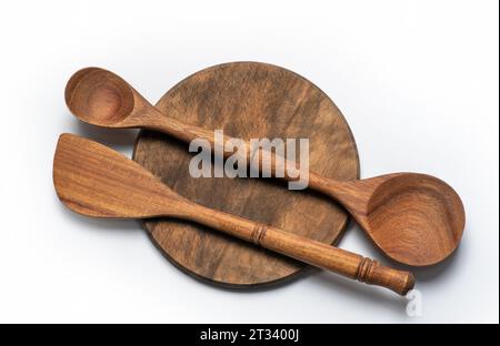 Rundbrett oder Pizzateller aus Holz auf einem Holztisch und zwei Holzlöffel zum Mischen von Lebensmitteln. Rustikales Küchenset Stockfoto