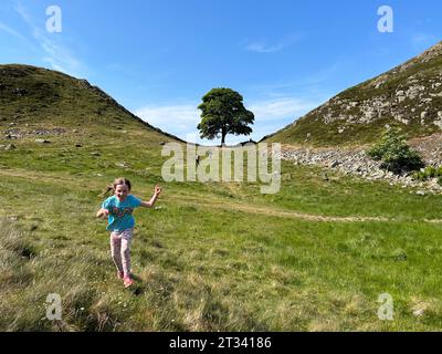 8-jähriges Mädchen, das freudig den Hügel in Northumberland, Großbritannien, runterläuft Stockfoto