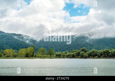 Berglandschaft mit einem See, Bäumen, umgeben von sich bewegenden Wolken. Stockfoto