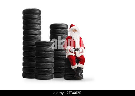 Der weihnachtsmann sitzt auf einem Haufen Autoreifen isoliert auf weißem Hintergrund Stockfoto