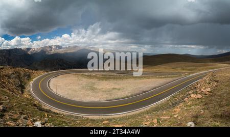 Panoramablick auf die kurvenreiche Straße mit Bergen und Sturmwolken Stockfoto