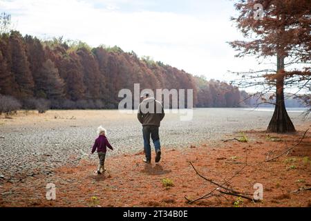 Vater und Tochter spazieren in der Natur am Herbsttag entlang des Sees Stockfoto