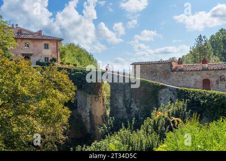 Nette Seniorin, die ihr E-Mountainbike in einem kleinen Dorf in der Nähe von Laterina in Val Darno, Toskana, Italien fährt Stockfoto