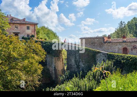 Nette Seniorin, die ihr E-Mountainbike in einem kleinen Dorf in der Nähe von Laterina in Val Darno, Toskana, Italien fährt Stockfoto