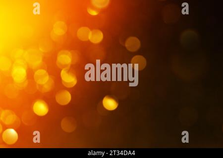 Orangefarbene, unscharfe Lichter und Partikel über dunklem, farbenfrohem, dynamischem Hintergrund. Stockfoto