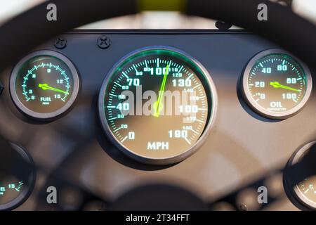Nahaufnahme des schwarzen Armaturenbretts des Rennwagens mit analoger Anzeige. Beweglicher Tachometerzeiger, der die Fahrgeschwindigkeit über 100 mph anzeigt. Sport, Power, schnell, Auto Stockfoto
