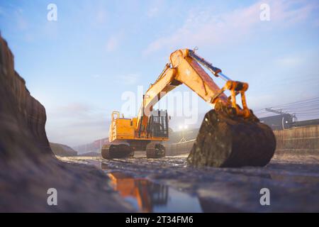 Bagger oder Bagger an sonnigen Tagen auf der Baustelle. Fracht- und Kesselwagen. Schwerbau, Abbruch, Graben, Bergbau, Landschaftsbau, und Stockfoto