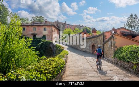 Nette Seniorin, die ihr E-Mountainbike in einem kleinen Dorf in der Nähe von Laterina in Val Darno, Toskana, Italien fährt Stockfoto