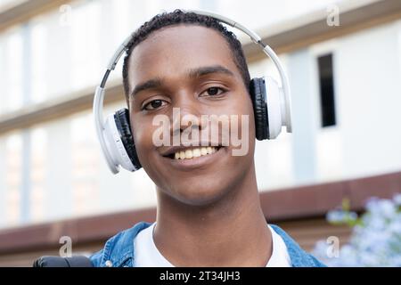 Nahporträt eines afroamerikanischen Teenagers, der auf dem Universitätscampus die Kamera lächelt. Stockfoto